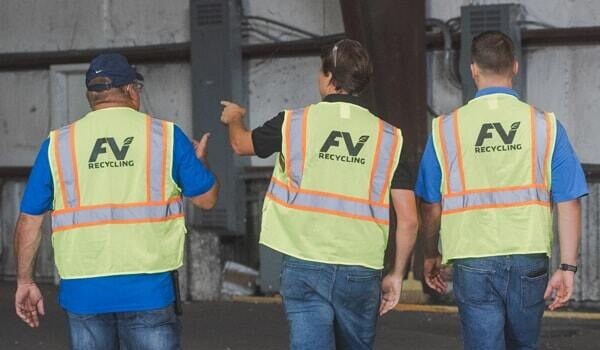 Three men from our team walking towards a warehouse with blue jeans and yellow FV Recycling safety vests.