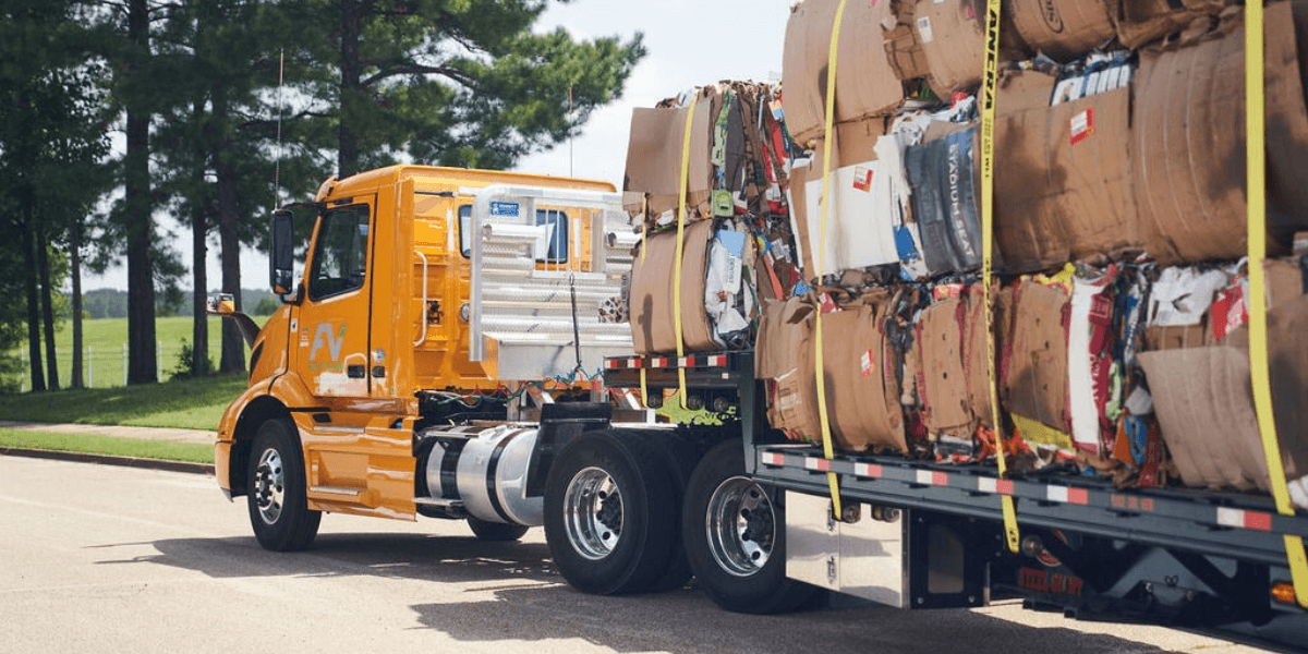 Yellow FV Recycling truck hauling bales of recycled material