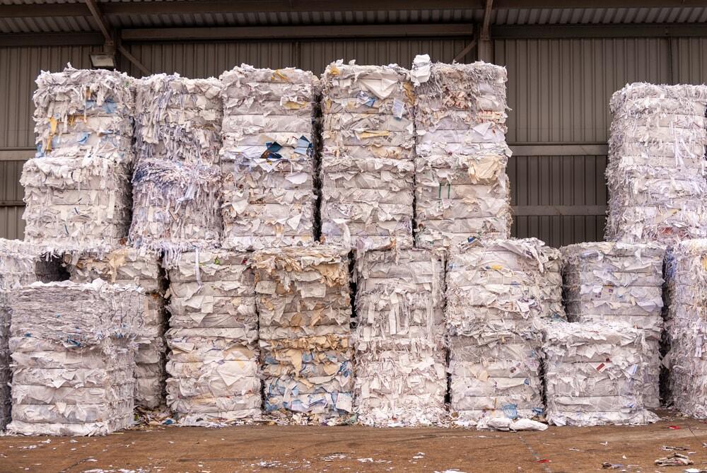 stacks of paper in bales piled up outside of a business under a covered area