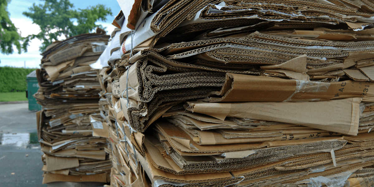 Two stacked of baled cardboard sitting outside being held together by bale wire.