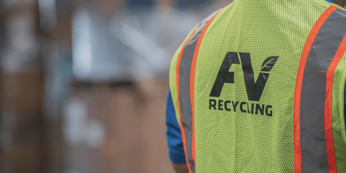 FV Recycling team member in safety vest at a recycling facility.