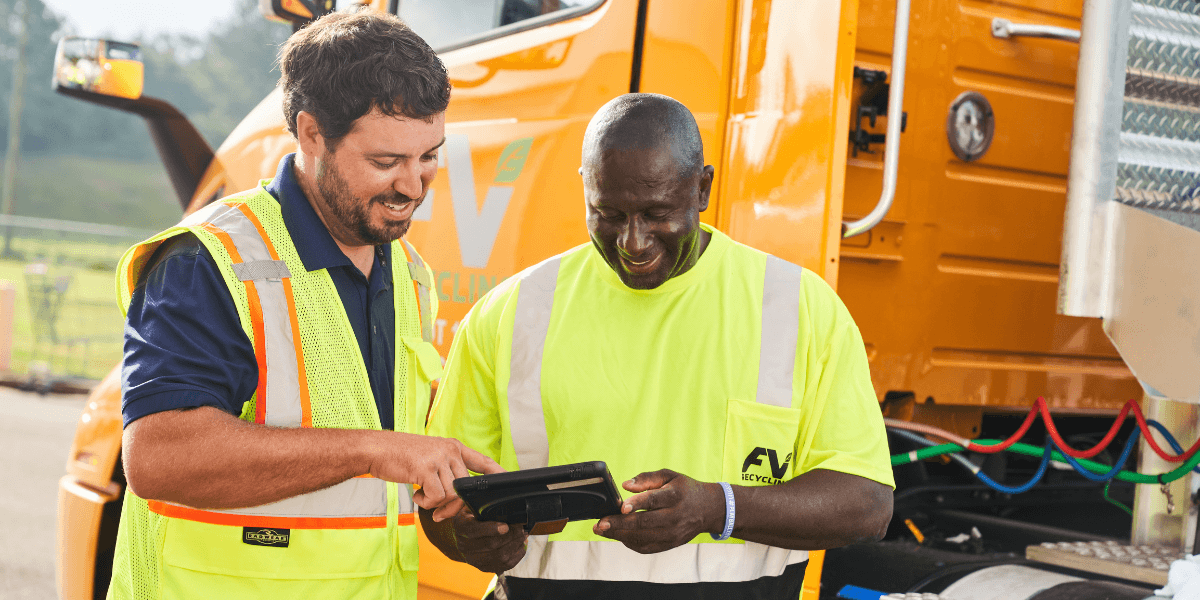 Two FV employeees in front of a bale route hauling truck looking at an ipad together. 